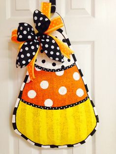 a door hanger decorated with an orange and black polka dot dress hanging on a white door