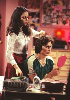 the young man is getting his hair combed by an older woman in front of him