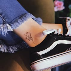 a woman's foot with a small flower tattoo on it