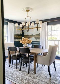 a dining room table with chairs and a chandelier hanging from the ceiling above it