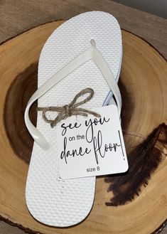 a pair of white flip flops sitting on top of a piece of wood next to a sign