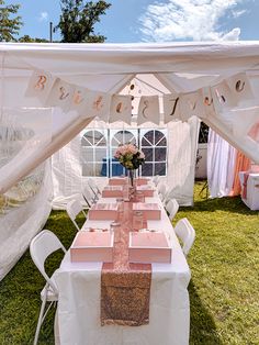 a long table set up with pink napkins and place settings under a white tent