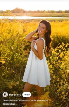 a beautiful young woman in a white dress posing for the camera with yellow flowers around her