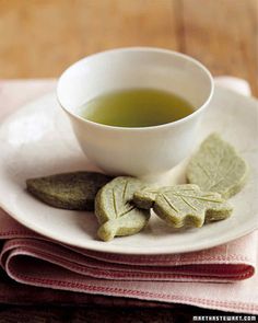 a white plate topped with cookies next to a cup of green tea