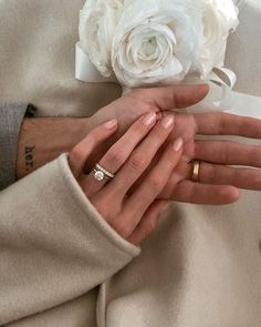 the bride and groom are holding each other's hands with their wedding rings on them