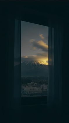 the sun is setting over a city as seen from an open window