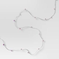 two pieces of white string with pink beads hanging from the end of each strand, on a light gray background