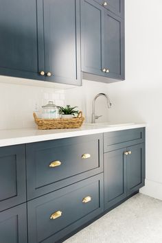 an image of a kitchen setting with blue cabinets and white counter tops, gold handles