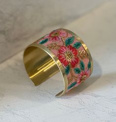 Soft pink flowers and gold embroidery create a dreamy vintage inspired cuff bracelet. This wide cuff bracelet makes quite the statement with it's delicately embroidered floral design. The beaded and thread accents give this cuff bracelet extra elegant details. • Handmade in India • Pink, coral, mint and gold embroidery • Statement making cuff bracelet in vintage design 1 5/8" wide Spring Gift Bangle, Gold Embroidered Bangle Bracelet, Gold Embroidered Bracelets For Wedding, Bohemian Embroidered Cuff Bracelet For Gift, Bohemian Embroidered Cuff Bracelet As Gift, Bohemian Pink Cuff Bracelet As Gift, Pink Bohemian Embroidered Jewelry, Bohemian Embroidered Pink Jewelry, Handmade Pink Cuff Bracelet For Wedding