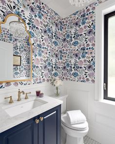 a white toilet sitting next to a bathroom sink under a mirror on top of a counter