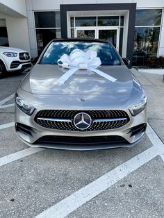 a mercedes car with a bow tied to it's hood in front of a building