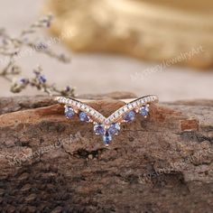 a close up of a ring on a piece of wood with flowers in the background