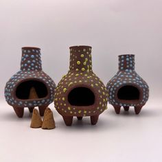 three ceramic vases with holes in them sitting next to each other on a white surface