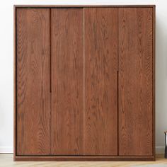 a wooden cabinet sitting on top of a hard wood floor next to a white wall