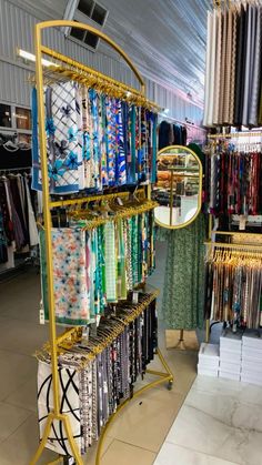 a rack with many different colored fabrics on it and a mirror in the corner next to it