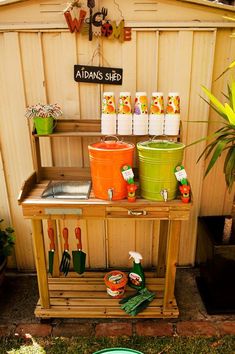 an outdoor kitchen with pots and pans on the shelf next to it, in front of a garden shed