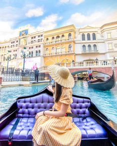 a woman in a yellow dress and straw hat is sitting on a blue boat with gondola