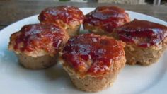 four mini meatloaf muffins with ketchup on top sitting on a white plate