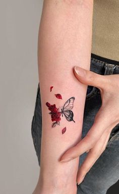 a woman's arm with a butterfly and rose tattoo on the left inner arm