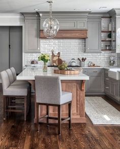 a kitchen with gray cabinets and white counter tops, wooden flooring and an island in the middle