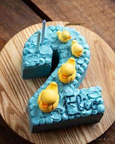 a cake shaped like the number two with yellow ducks on it and blue icing