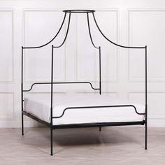 an iron bed frame with a white mattress underneath it and wall paneling in the background