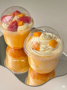 two desserts are sitting on top of each other in plastic cups with fruit toppings