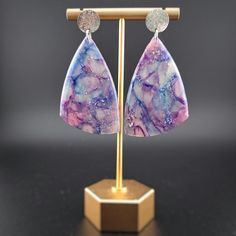 These translucent earrings are beautiful in any light, but they absolutely stun when graced by the sun. Threads of lavender, turquoise, and magenta dance through each piece. They are a great gift for anyone wanting to embrace their whimsical side with a touch of elegance! They are handmade and unique--no two have the same design. They are lightweight, which makes them a thoughtful gift for anyone who has trouble with heavier earrings. Each earring is made by hand and will have slight variations in the pattern. All of my materials are nickel-free and hypoallergenic. Reika means "wander" in Icelandic, and being a wanderer is crucial to my existence. As such, all of my pieces are imbued with parts of the natural world that have inspired me. It is my hope to provide this same inspiration to an Handmade Iridescent Drop Earrings, Unique Iridescent Teardrop Earrings, Unique Iridescent Earrings, Unique Iridescent Pierced Earrings, Unique Iridescent Earrings For Party, Handmade Purple Resin Jewelry, Unique Purple Earrings With Ear Wire, Bohemian Iridescent Earrings With Ear Wire, Iridescent Bohemian Earrings For Gifts