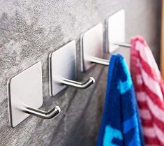 three towels are hanging on the wall next to two towel racks and one is holding an umbrella