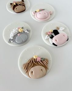 four decorated cookies with farm animals on them sitting on a white table top in the shape of circles