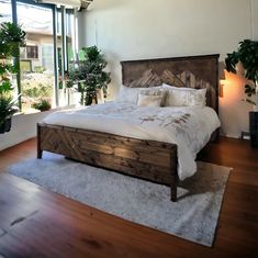 a large bed sitting on top of a wooden floor next to a plant filled wall