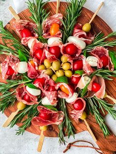 a wooden platter filled with meats and veggies on skewers