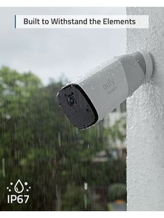 an outdoor security camera attached to the side of a building with rain falling on it