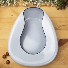 a white toilet bowl sitting on top of a wooden floor next to flowers and nuts