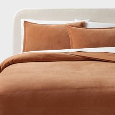 a bed with two pillows on top of it and a brown comforter in the middle