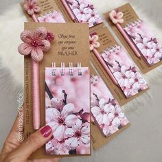 a hand holding a notebook with pink flowers on it, and four notepads attached to the cover