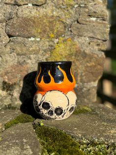 a black and orange vase sitting on top of a stone wall