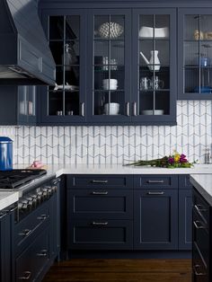 a kitchen with dark blue cabinets and white counter tops, an open spice rack in the middle