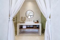 a bathroom with a sink, mirror and white curtains