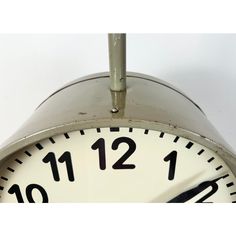 an analog clock is hanging from a metal pole with numbers on the front and sides