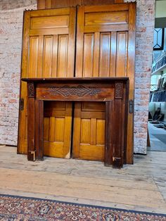 an old wooden fireplace with two doors and a rug on the floor next to it