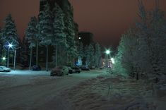 cars parked on the side of a snowy road at night