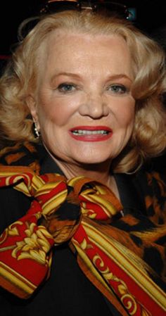 an older woman wearing a red and gold scarf with a big smile on her face