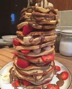 a stack of pancakes covered in chocolate and strawberries