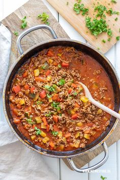 a pot filled with meat and vegetables on top of a wooden board next to a cutting board