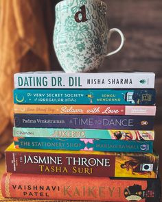 a stack of books sitting on top of a table next to a cup and saucer