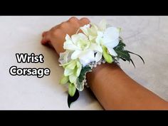 wrist corsage with white flowers and green leaves on the wrist for brides