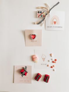 some pins and magnets are on a white surface next to each other, including one with a red heart