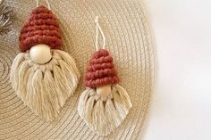 two knitted gnomes hanging from hooks on a straw hat