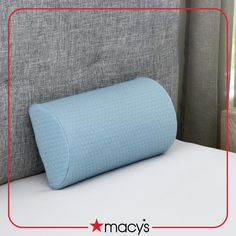 a blue pillow sitting on top of a bed in front of a gray headboard